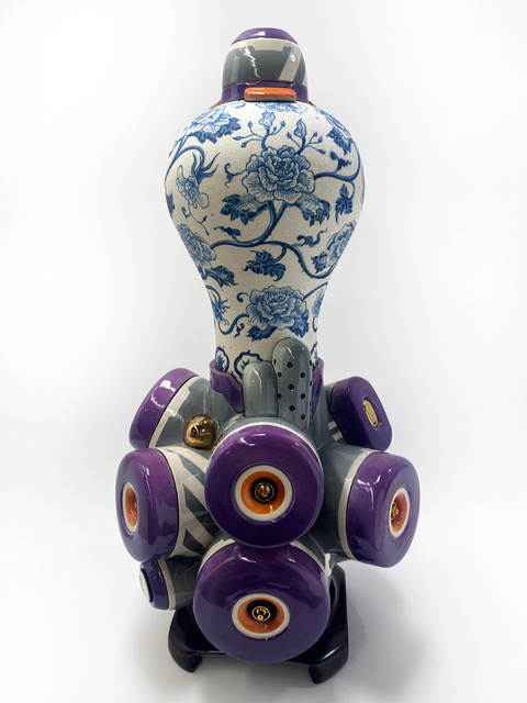 White and blue ceramic art that resembles fine China, with purple, red and yellow modes at the bottom.